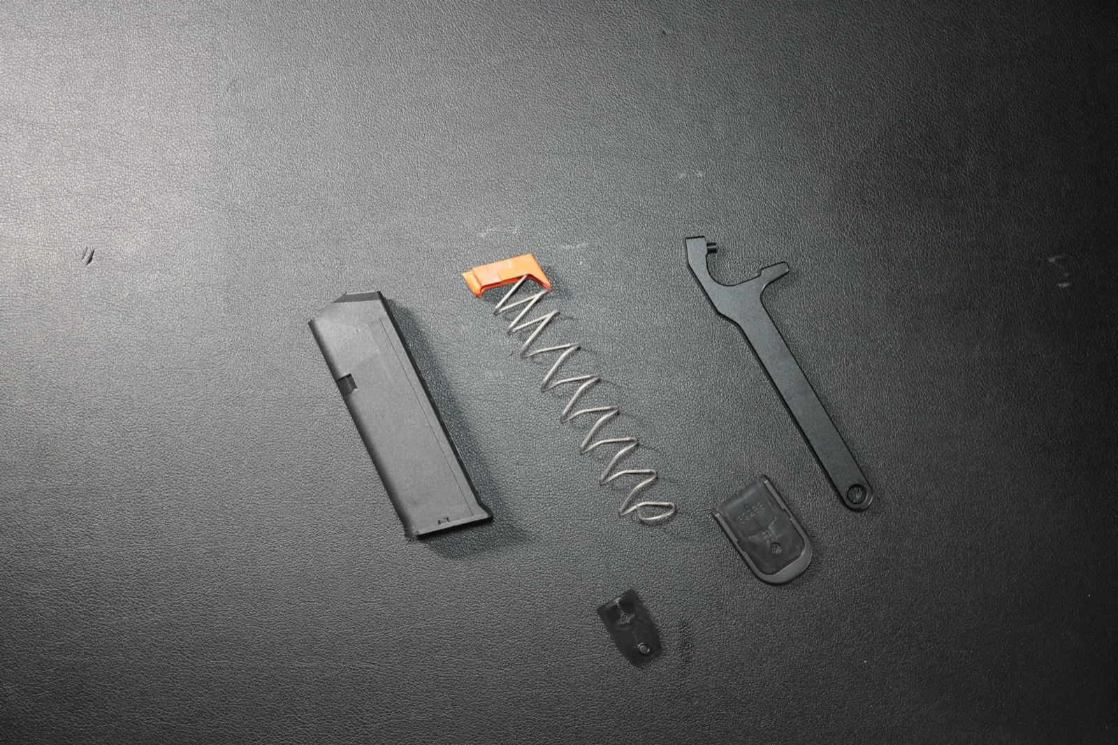 Standard Glock magazine fully disassembled into body, follower, spring, insert, and floor plate