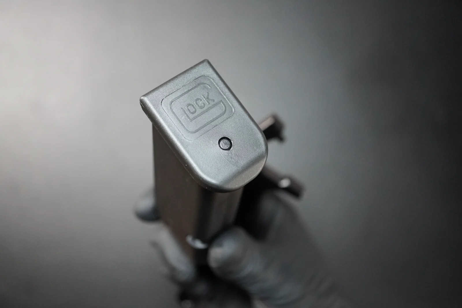 Bottom of an assembled Glock magazine showing the floor plate and access hole — start state